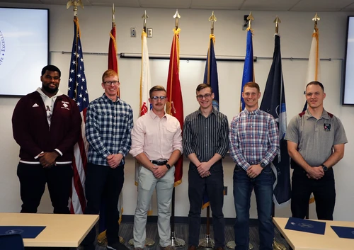 Group of people in front of flags. 